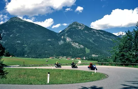 Motorräder in einer Kurve im Namloser Tal vor Bergkulisse Motorräder in einer Kurve im Namloser Tal vor Bergkulisse
